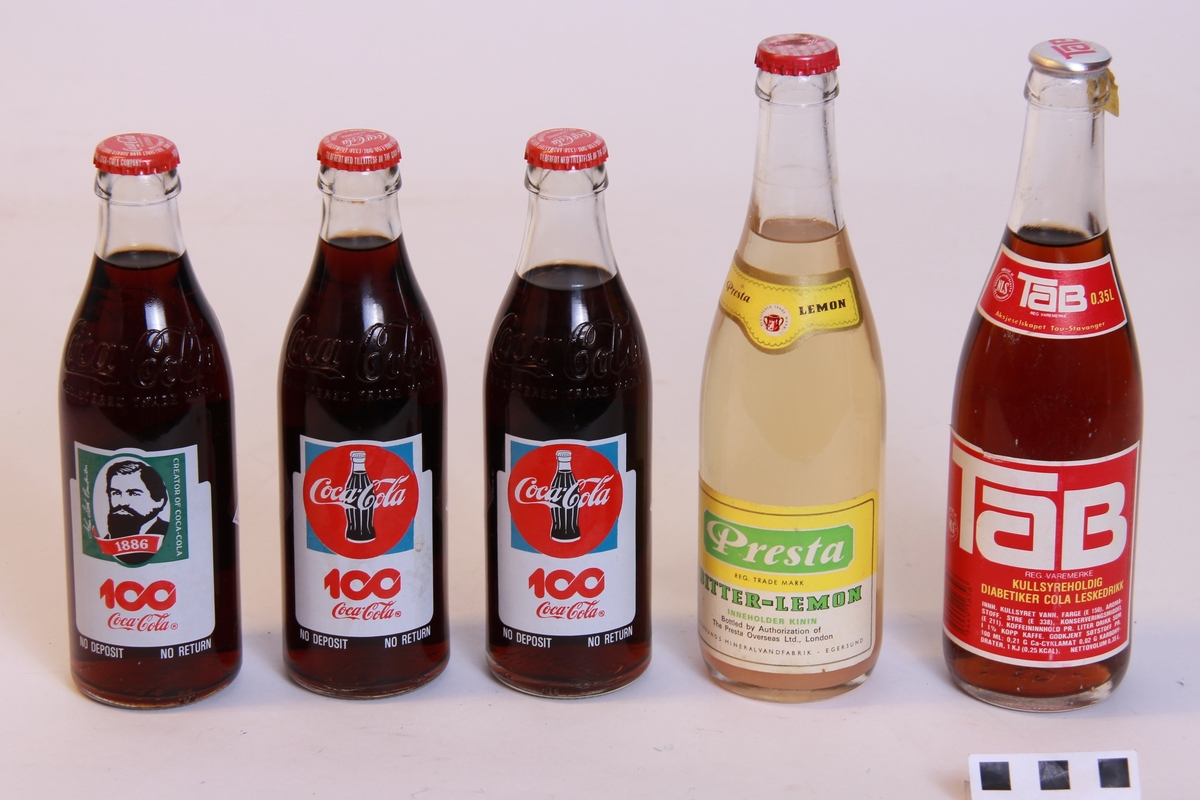 5 uåpna brusflasker.
3 flasker Coca Cola, 100-års jubileumsflasker, 296ml (a)
1 flaske Tab, 350ml (b)
1 flaske Presta Lemon, 350ml (c)

Tab-flaska har rive-flik på korken