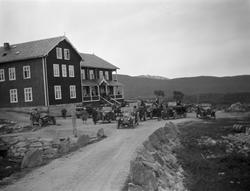 Biler og mennesker står på plassen utenfor Grotli Hotell.