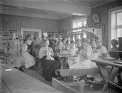 Håndarbeidsundervisning av en gruppe jenter.