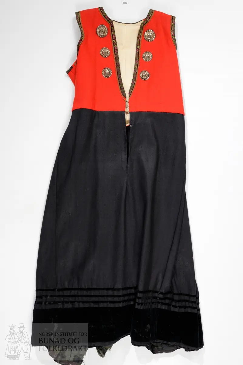 Liv sauma av raud ullkypert, lett valka. Fora med ubleika bomullslerret.
Ermhole, rundt hals og opning framme er kanta med blomstermønstra fleirfarga fløyelsband med svært avslitt fløyel. Innanfor kantingar er det påsett eit smalt metallband.
Etter framkantane er det påsett 3 borer på kvar side, dei to øverste litt breiare enn dei fire nederste, alle har eit skåleforma lauv festa i midten. På framsida av den kurva delen er det fem ulike stempel: 63 i eit sirkelforma stempel, truleg årstalsstempel. Månadsstempel: 6 over M i rektangelforma stempel. Mesterstempel i bølgeforma ramme LAR, Lorentz Christopher Angel Reimers, fekk borgarskap i Bergen i 1832. Lødighetsstempel 13 1/3. Trapesforma stempel med 7 prikkar, Bergens bystempel.
Lukking framme med to metallhekter på kvar side.
Heile livet er sauma på maskin. Kanting er sauma for hand. 
Livet sauma på stakken for hand. 
Stakken er av heimevove ullerret, blåsvart. Splittopning midt framme. Samansett av 5 rette høgder med jare i begge sider, alle høgder. Faldelagt oppe med eit glatt felt framme mot splitt. Høgdene er sauma saman med maskin. 
Nedkant: 3 svarte smale sillkefløyelsband, nedanfor dei eit påsett stoffstykke av svart bomullsfløyel. Dette stoffet er ein hengefald, ikkje sauma fast i nedkant.
Nedkanten er skonna på innsida med eit lerretsvove mohairstoff av mørk grøn farge. Sauma på med maskin. I nedkant av skonninga er det påsett eit blåsvart kosteband sauma på for hand.
Kanten på linninga er av svart bomullssateng. Er bretta dobbelt og sauma på for hand på begge sider