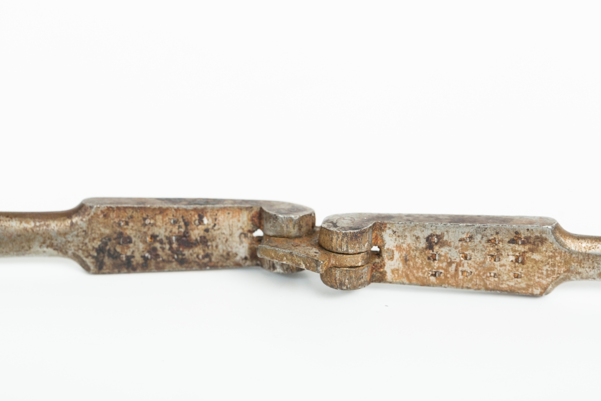 Nøteknekker i stål uten dekor. Utslåtte knaster på "gripeflatene". Hengsel med avstandstykker for to knekkeavstander.