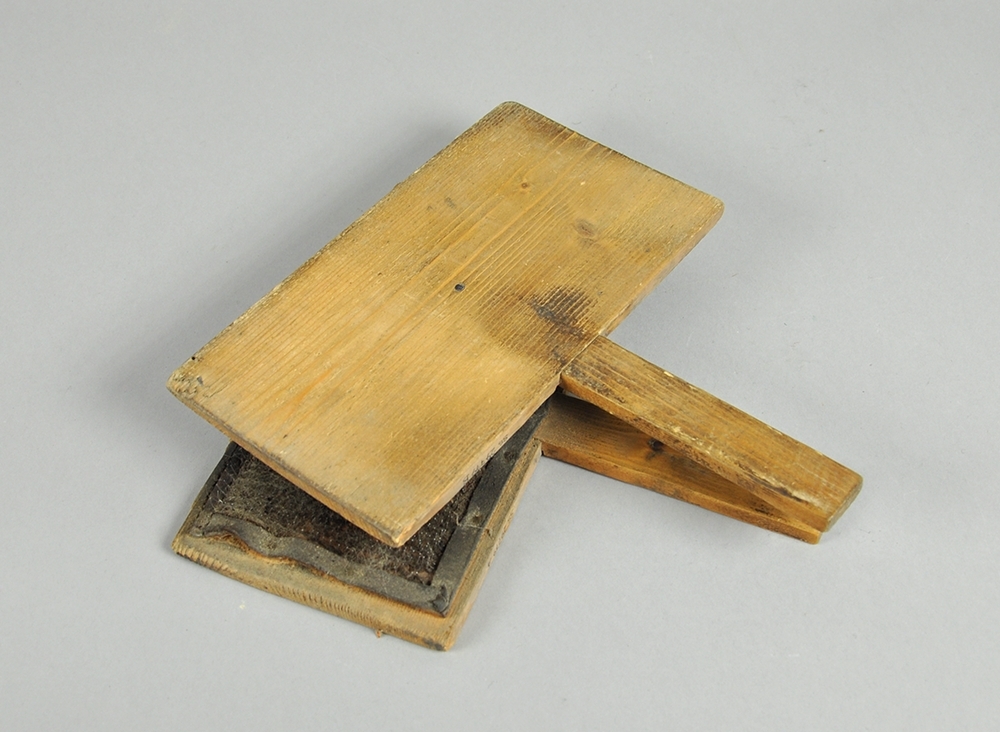 To treplater hvor innsiden av begge platene er dekket av en skinnduk med tettsittende nåler. Begge treplatene har håndtak.