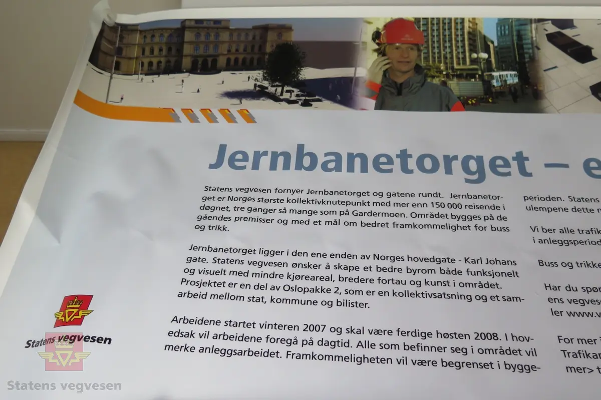 Rektangulær flerfarget plansje av plastlignende materiale, maljer i hvert hjørne. Tekst forteller om prosjektet med fornyelse av Jernbanetorget og gatene rundt.