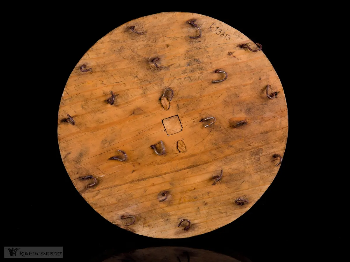 Sirkulær treplate med en dreid trehåndtak med metallhempe. Flere metallkroker er festet på undersiden for festing av lysveker.