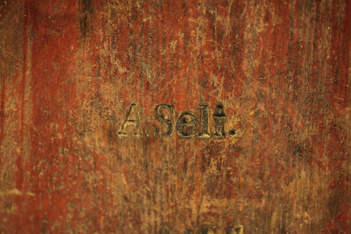 Lagget med 2 gjorder, men den øverste er borte. Bevegelig tverrhank med tretapper, to ører og innfelt bunn. Formen er rund, sylinderformet, uten lokk eller ben. Har vært påmalt rød farge. Brukt til melk.