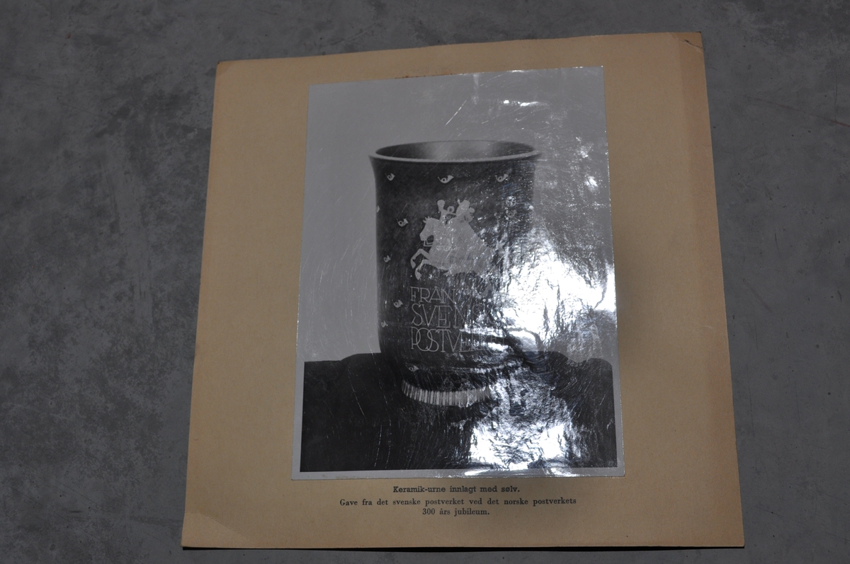 Bilder av framside og bakside av en urne som er gitt av Svenske Postverket i forbindelse med Postens 300 års jubileum.