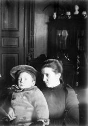 kvinne, barn med lue, stue ca 1900. Samlingen har tillhørt G