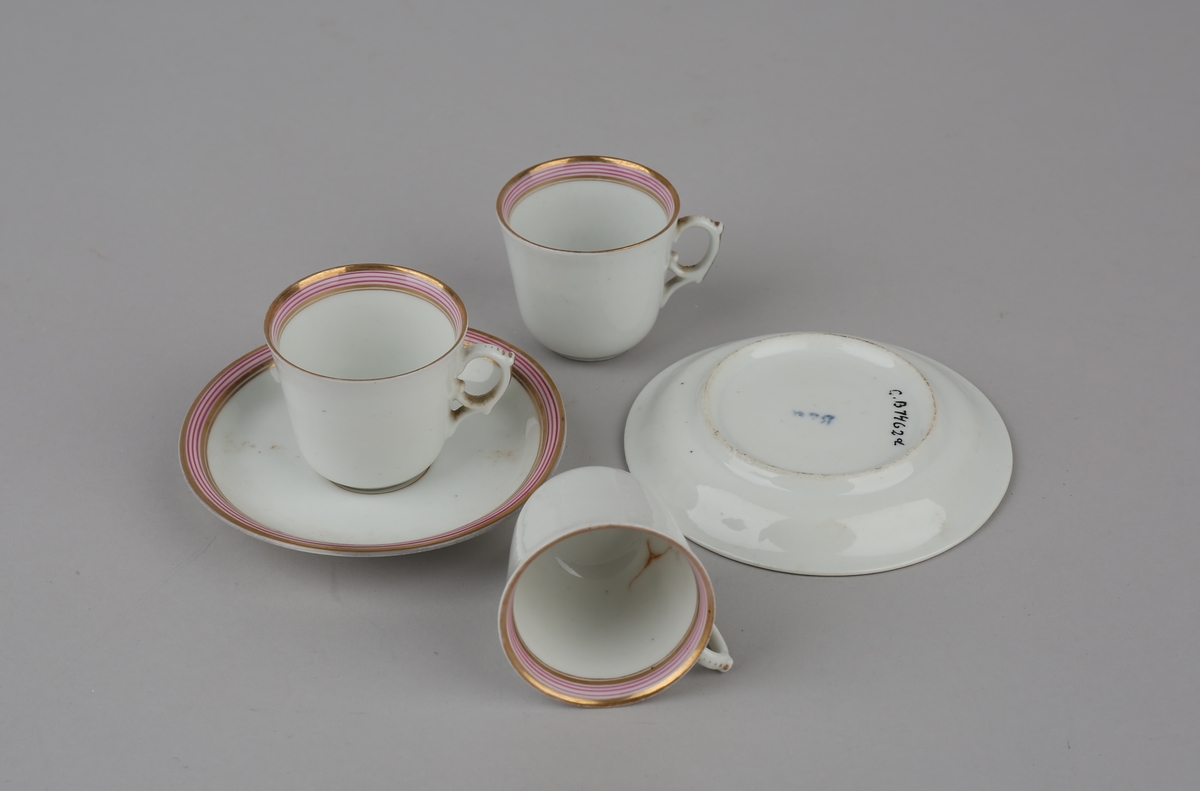 Dukkeservise bestående av 3 kopper og 2 tefat/underskåler i hvit porselen med gull og rosa langs kanten.