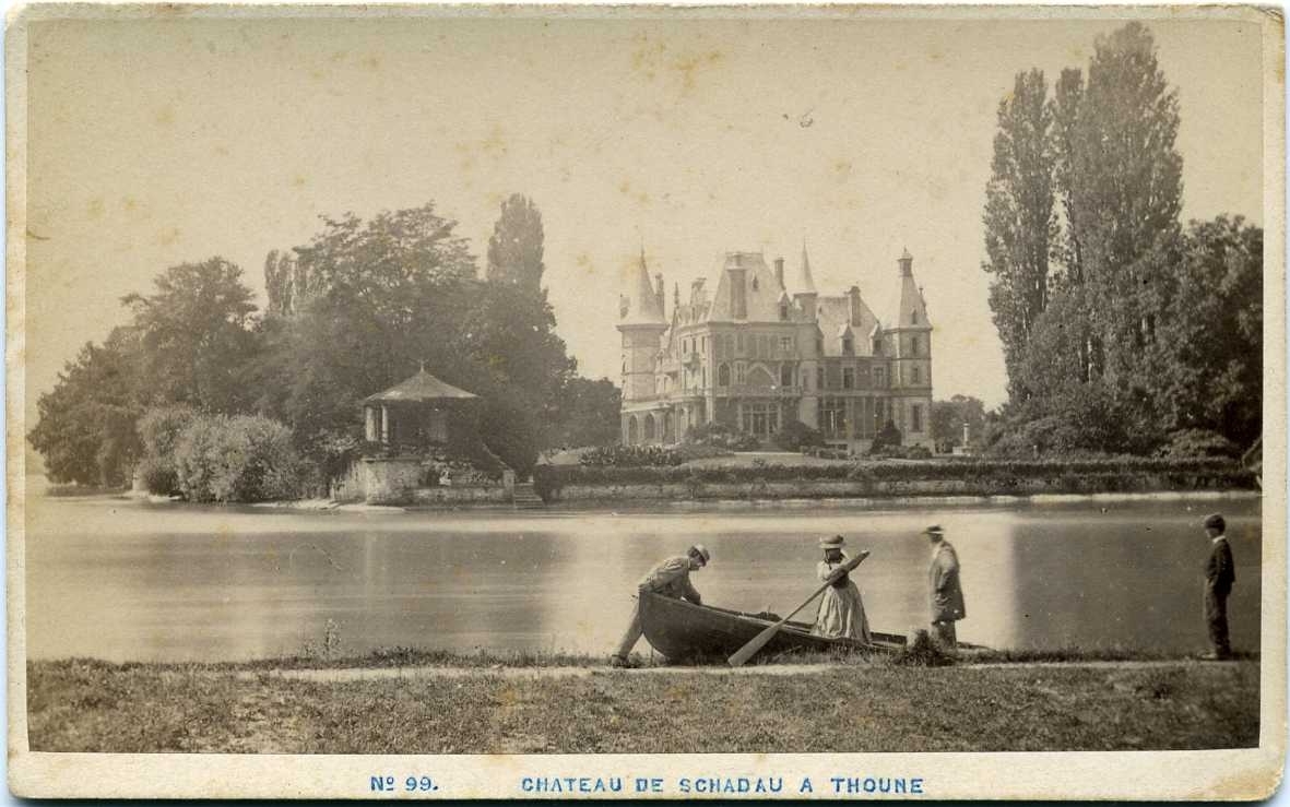 Kabinettsfotografi: En eka med en kvinna och några män lägger ut i en sjö framför slottet Chateau de Schadau A Thoune.