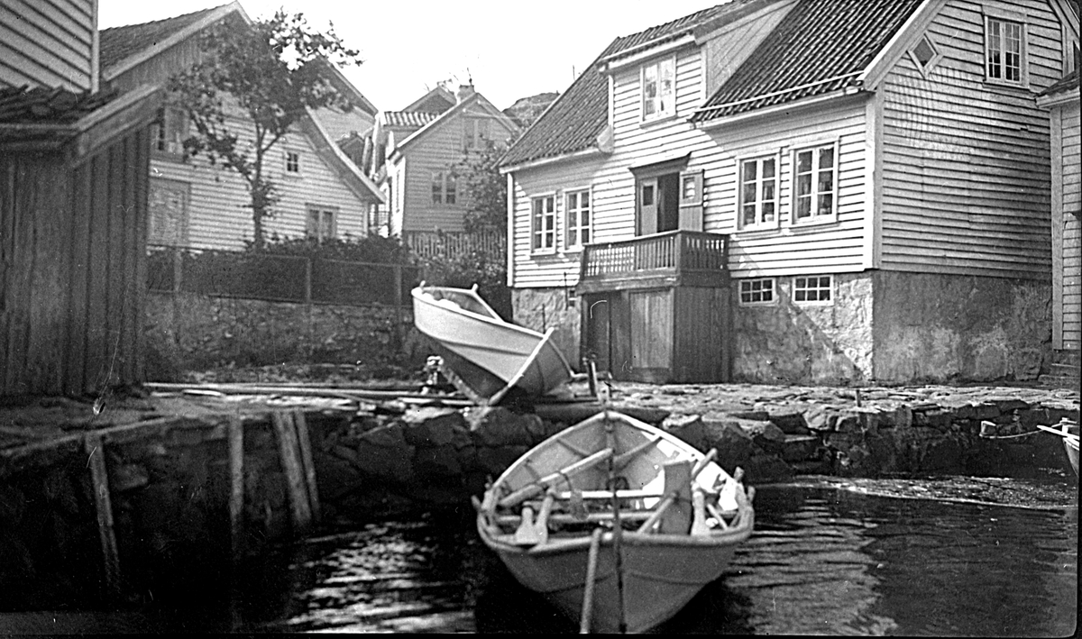 Nedenfor Rennesåga i Loshavn ligger en båt fortøyd. En annen båt er dratt på land foran et hus.