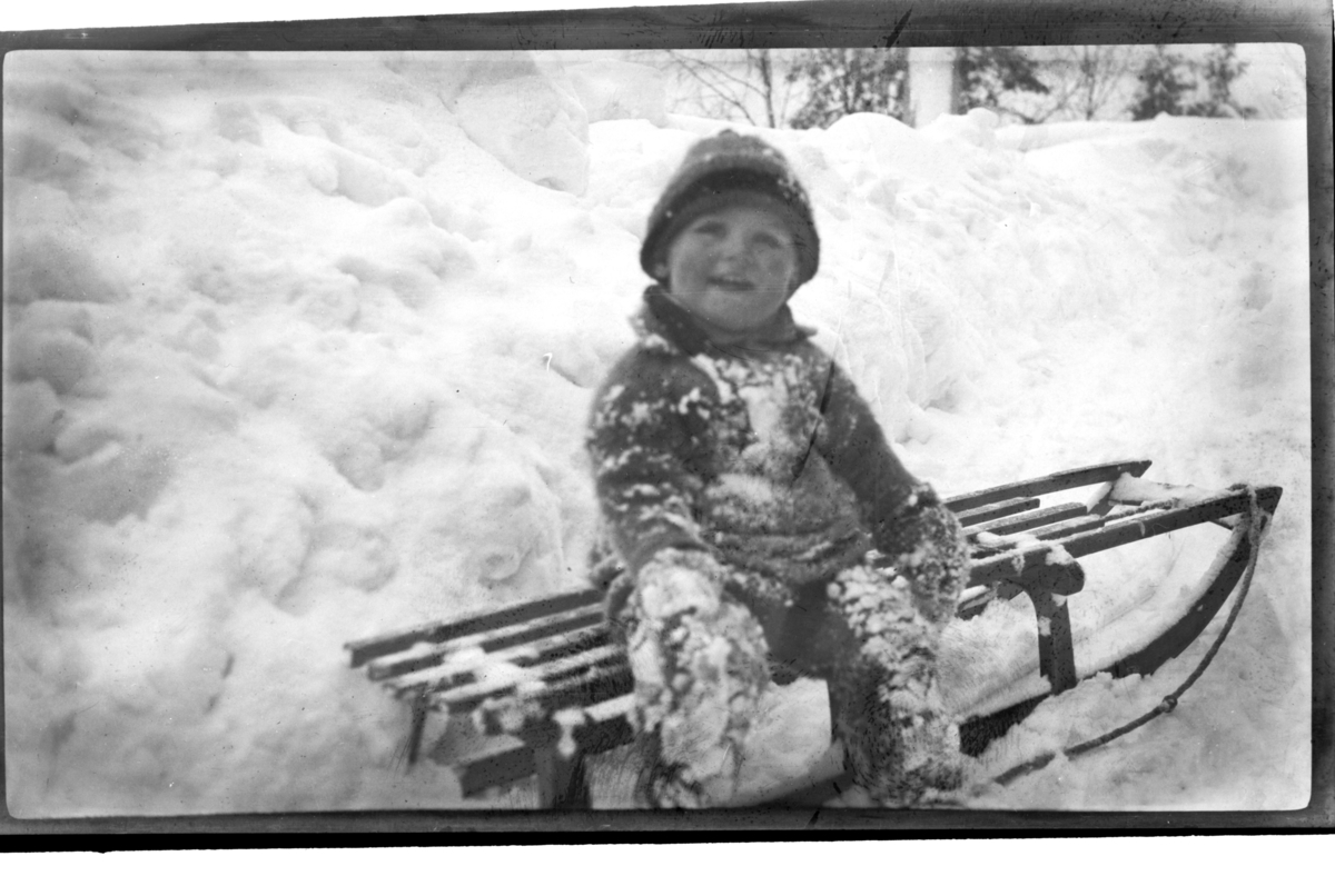 Julius Sundt sitter på en kjelke med masse snø rundt seg, Ville Knyggen. Fotografert 1918-1919.
