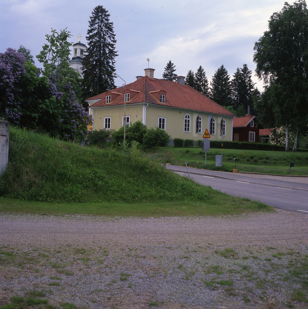 Rengsjö församlingshus med kyrkans torn i bakgrunden, juni 1999.