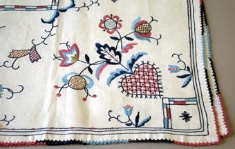 Bordsduk med broderad dekoration i flera färger.