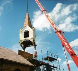 Spiret på kirken heises opp på taket med en heisekran
