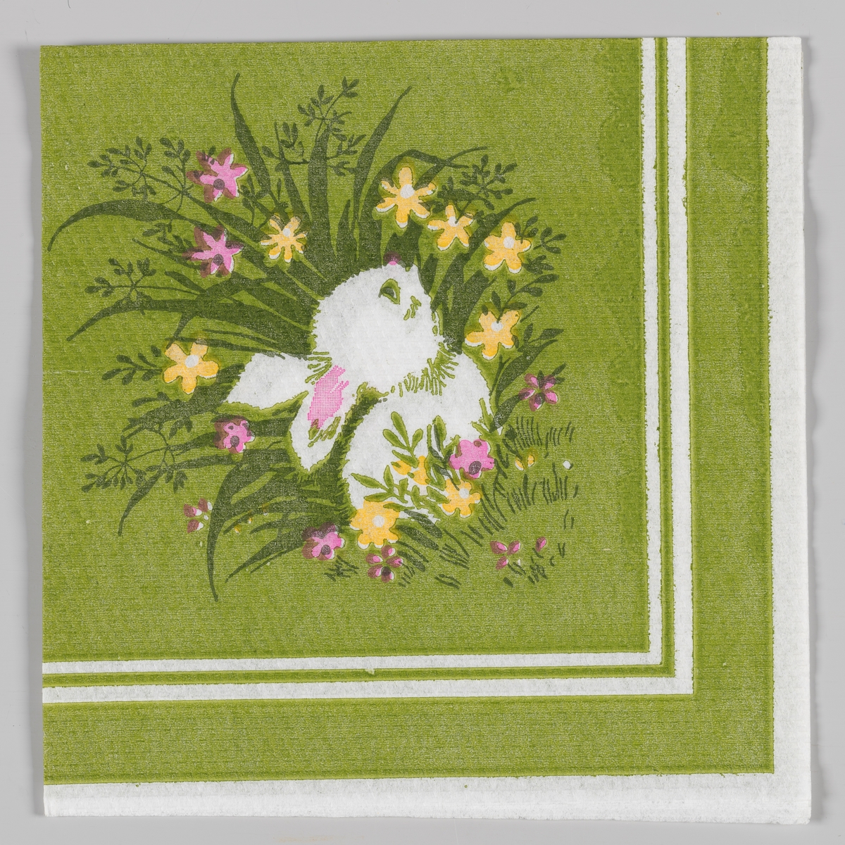 En liten harepus som gjemmer seg i høyt gress med gule og rosa blomster. Hvite og grønne kantstriper.