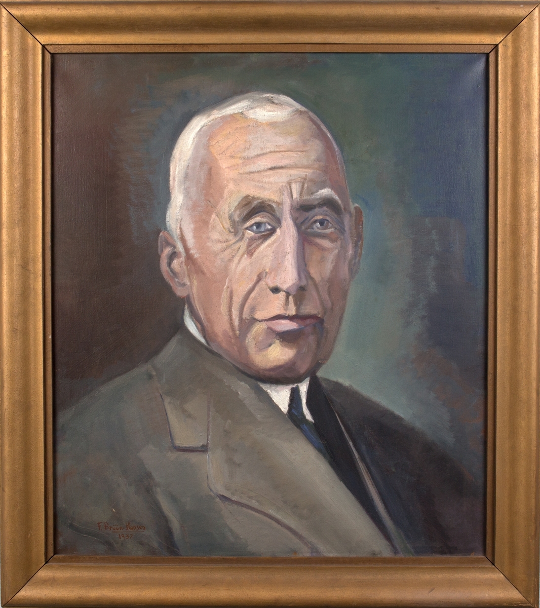 Brystportrett av Roald Amundsen. Han er hvit i håret, og er iført lys dressjakke, hvit skjorte og blått slips.