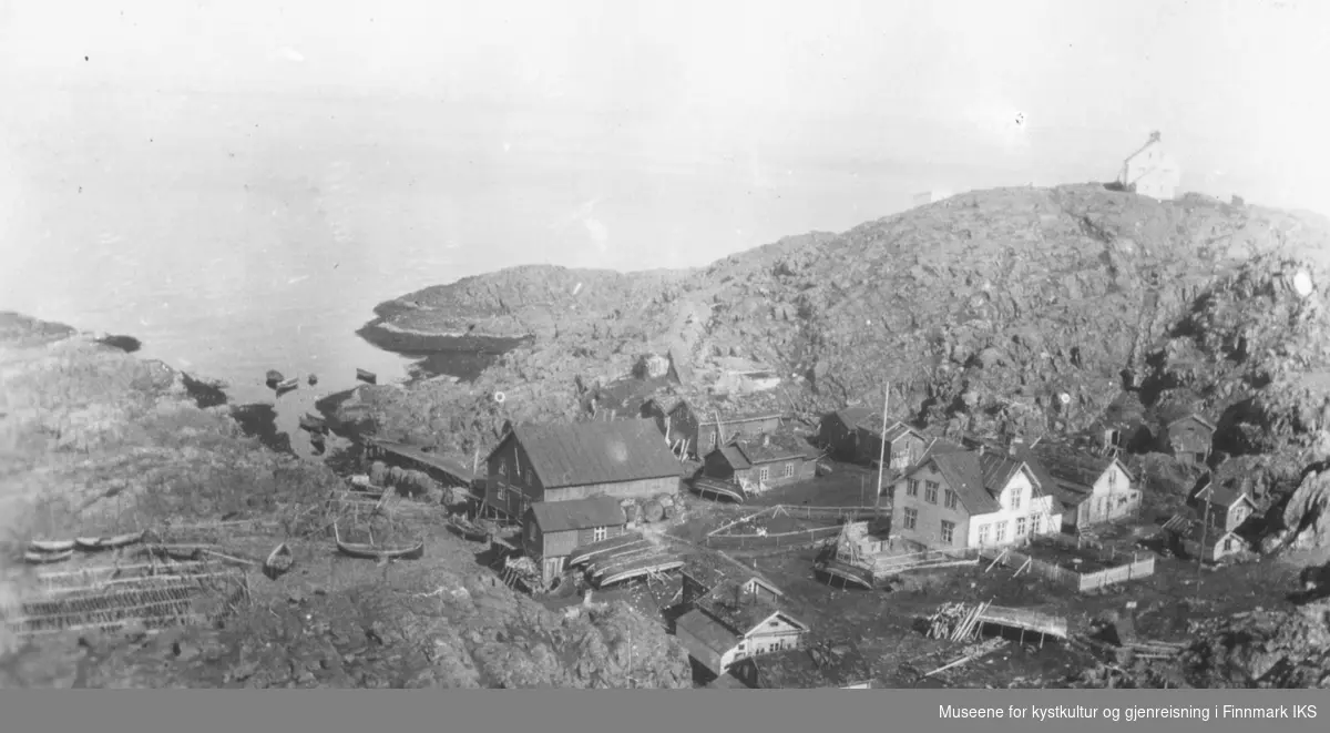 Helnes med bebyggelsen, båter som ligger på land, fiskehjeller og på toppen t.h. ser man Helnes fyr. 1910-1944.