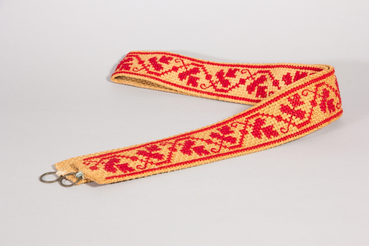 Brickband, 2 st, av naturfärgad juteväv med korsstygnsbårder i rött. Ringar för upphängning.