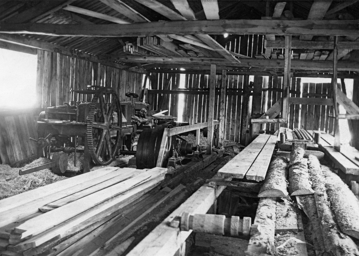 Interiør fra Sørgården sagbruk og høvleri i Hattfjelldal i Nordland, fotografert i 1927.  Sagbruksbygningen var en bordkledd bindingsverkskonstruksjon, med en stor åpning i den ene langveggen for inntak av tømmer (til høyre for høyre bildekant på dette fotografiet), og en mindre lysåpning på den veggen som vendte mot vassdraget (til venstre på bildet) .  Energi til saging og høvling ble hentet fra ei vassrenne, som ledet vann mot et roterende vasshjul, som satte et system av akslinger og drivreimer med forbindelser til sag og høvel i bevegelse.  Til høyre på dette fotografiet ser vi en todelt sagbenk med underbygning, ruller, brett (forbrett og styrebrett uten tverrlister) og overdekning av tre.  Stillverket, som brukes til å regulere tjukkelsen og bredden på bord og planker, var imidlertid utført av støpejern.  Det er rimelig å anta at stokkene på dette sagbruket ble kantet på den ene sida av sagbenken og kløyvd på den andre.  Da dette fotografiet ble tatt lå det en del korte, ubarkete hunbord mellom de to sagbenkene.  Til venstre i bildet lå det en del korte, nyskårne bord på golvet, hvorav enkelte hadde vankant.  Bakenfor ser vi en høvelmaskin av støpejern, som skal ha vært den eneste kutterhøvelen for trelast i Hattfjelldal da dette fotografiet ble tatt.  Ved siden av høvelen (til høyre) ser vi ei diger reimskive med en aksling som lå på golvet.  På takstolenes undergurter lå det en del bord.