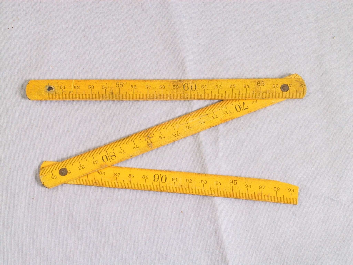 Samanbrettbar tommestokk med centimeter- og tommeinndeling.