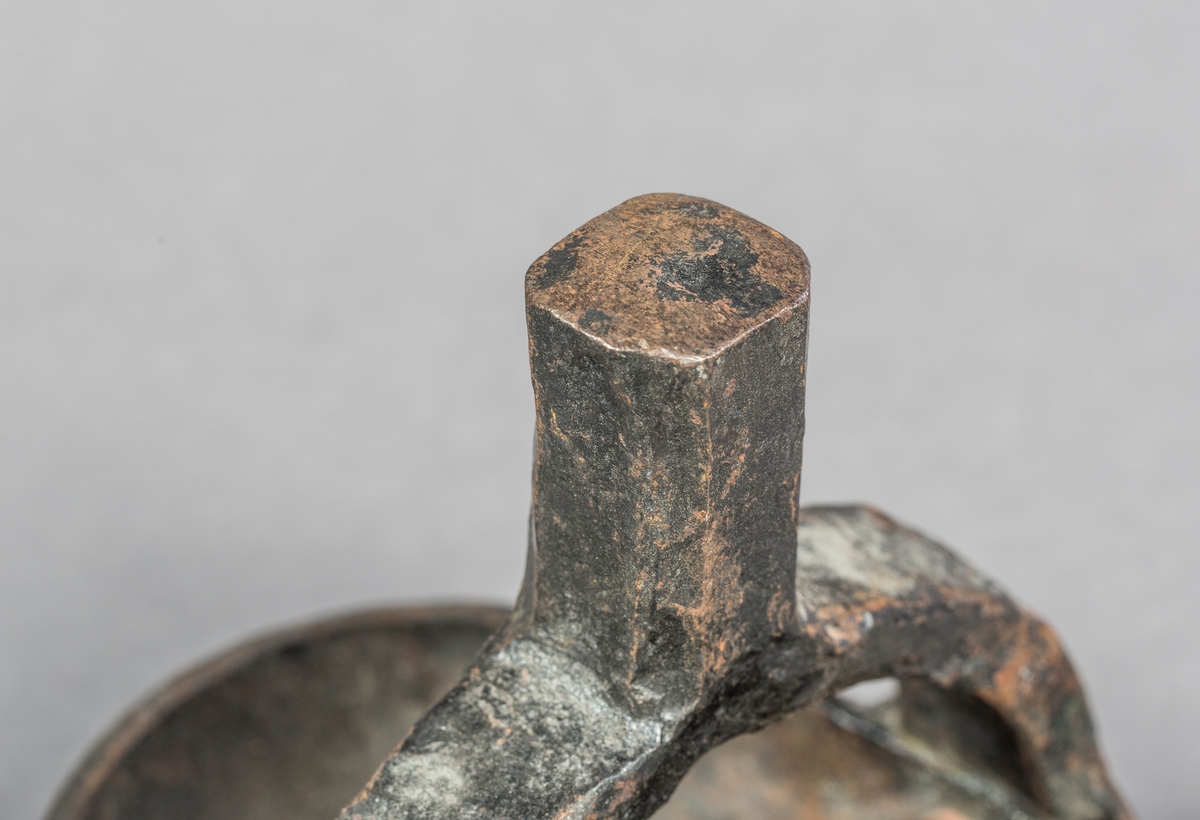 Ovalt jern med fastnaglet håndtak på bue på oversiden.