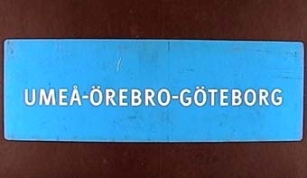 Långsmal dubbelsidig skylt av blå plast med vit text: "GÖTEBORG - UMEÅ"

Text på andra sidan:

"UMEÅ - ÖREBRO - GÖTEBORG"
