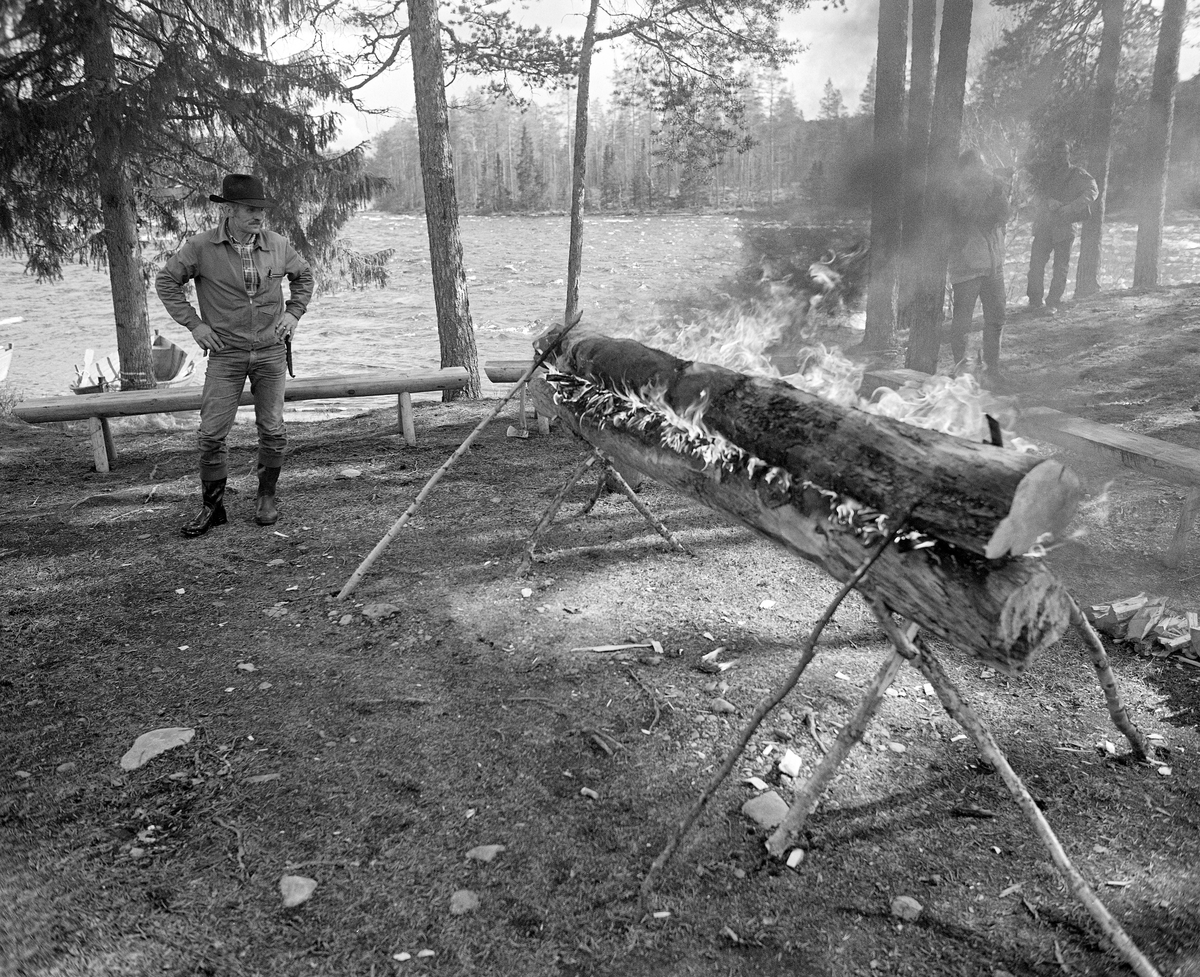 Brennende nying ved Stenbekkoia ved Femundselva i Engerdal i mai 1986.  Denne nyingen ble oppsatt og tent som en del av programmet da styret i Klarälvegns Flottningsförening hadde sin ekskursjon langs vassdraget dette året.  Nyinger består av en eller flere horisontalt- og paralleltliggendende stokker, lagt og nørt slik at de skal gi god og vedvarende varme.  Slik ild ble brukt i skog og utmark.  Vinterstid overnattet skogsarbeiderne vanligvis i hus – skogstuer eller koier – med mildt sagt enkel standard.  Men i vårsesongen forekom det ikke sjelden at fløterne sov under åpen himmel og hentet varme og tørk fra nyinger. I en medisinalberetning fra 1871 beskrev distriktslege Christian Pavels Munthe (1816-1884) i Elverum nyingen slik:

«Ikke altid kunne de vaade og forfrosne Flødere finde varmt og beboet Hus til Natten, - ikke engang en Køie, hvor de kunne tørre sine Klæder og finde et varmt Leie.  Meget ofte maa de lægge sig vaade som de ere paa den vaade Jord med et Lag af Barkviste under sig, efterat have opgjort en Ild  - «Nying» - paa følgende Maade: De tage en tyk, letbrændelig Stok, hvorover de lægge en anden noget mindre af samme Slags.  Disse to Stokke holdes fra hinanden ved to eller flere Stykker Træ ved Enderne («Beitkøler»), medens den øverste hindres fra at falde ned ved paa hver Ende at støttes ved tvende længere Kabber, der som Strævere lægges på imod den.  En saadan Kabbe kaldes «Haldmær» og mellem de saaledes ovenpaa hinanden liggende Stokke opgjøres paa flere Steder Ild, der langsomt brænder og underholde Varme den hele Nat.  Fløderne lægge sig nu paa begge Sider af en saadan «Nying», og vende sig gjentagne Gange om Natten, for at snart den ene, snart den anden Side kan blive varmet og tørret ved Ilden.»

Nyingene kunne lages av en eller flere stokker, og var det flere enn to, ble de ofte lagt slik at nyingen fikk et pyramidalt tverrsnitt.  I dette tilfellet var det en to-stokknying, der den underste stokken sto på et trefotet stativ av kjepper.  Oversida av denne stokken og undersida av overstokken var fliset opp ved hjelp av ei øks, og i mellomrommet mellom dem lå det tørre flister, som skulle lette antennelsen.  Den øverste stokken var støttet med skråstivere av kjepper på begge sider.  Da dette fotografiet ble tatt sto arbeidsformann Kåre Joar Graff og betraktet den brennende nyingen.
