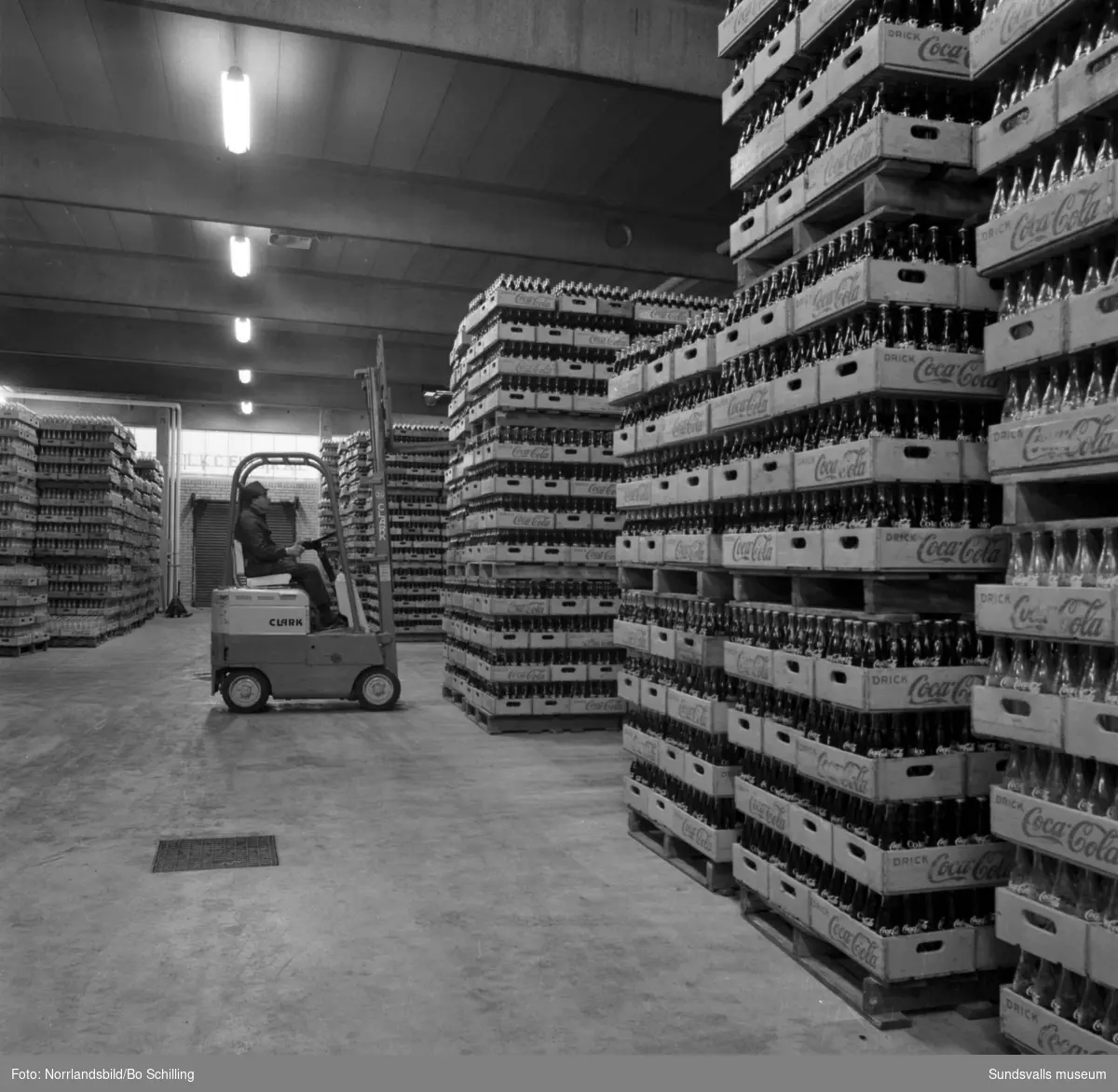 Coca-Cola-fabriken vid Bultgatan i Nacksta. Exteriörbilder samt bilder från lagret, en man kör truck bland tomma och fyllda flaskor.