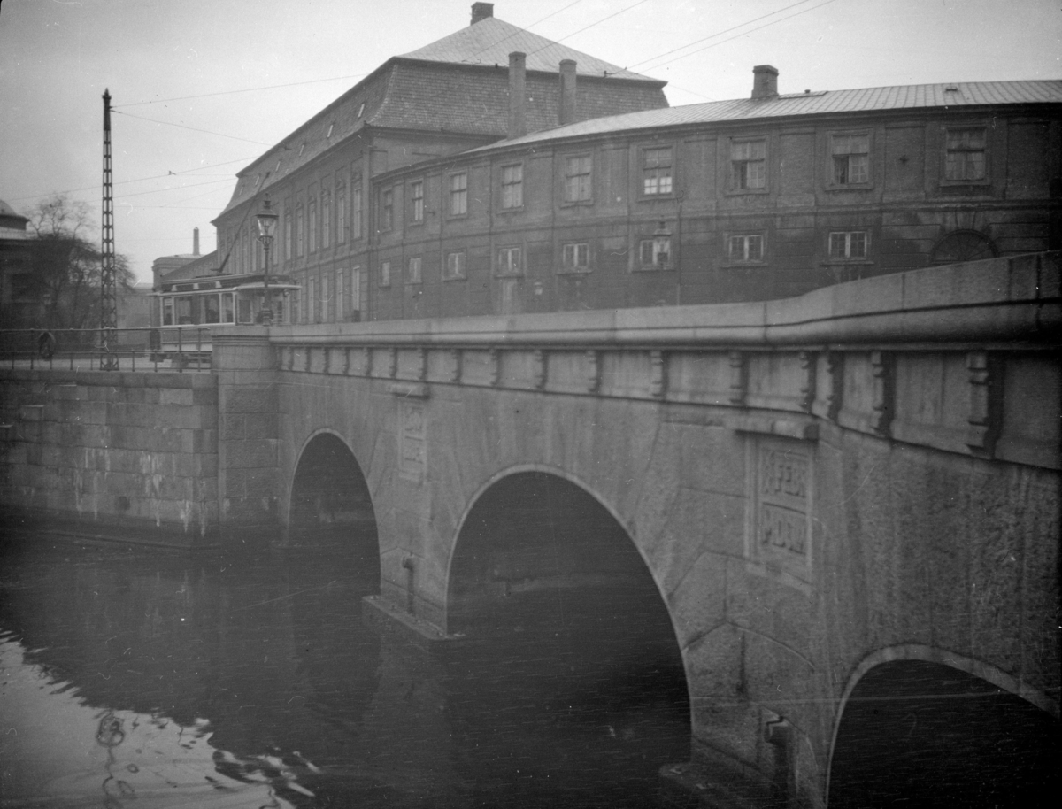 København, Danmark. Brua til høyre er Stormbroen, som går over Fredriksholms kanal. Trikken er på vei inn i den gata som mange år seinere fikk navnet Vindebrogade. Det buede bygget til høyre er en del av Nationalmuseet. Helt til venstre en snipp av Thorvaldsens museum. Trikken er en såkalt hovedtypevogn levert 1901 - 1907 (265 vogner). De mørke skiltfargene tyder på at det er linje 6.