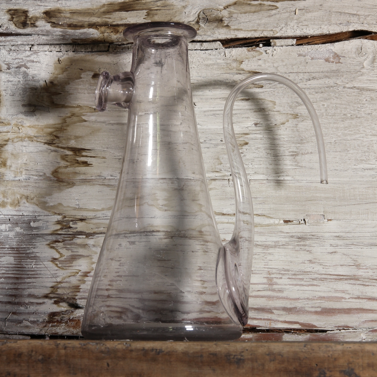 Destillationskärl av klart glas med nedtill kraftigt svängt rör. Under mynningen en kort pip,