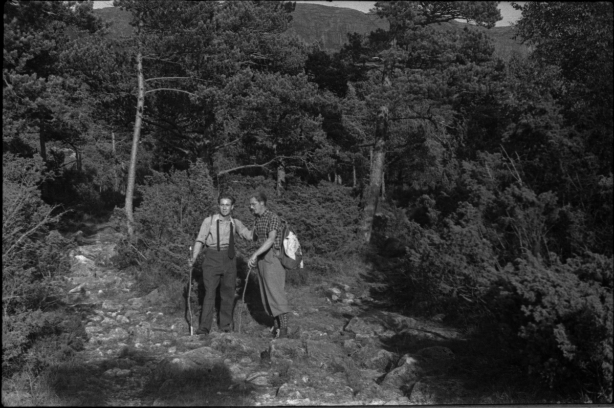Anton Birkemo og en mann under kallenavn "Skotten" på tur mellom Preikestolen og Bratteli ved Lysefjorden. Det er bilder av fjellformasjonser som Hyvletomma (?), Preikestolen, Hengjafjell og Hengjanibbene, og turister som besøker Preikestolen og Hengjafjell.