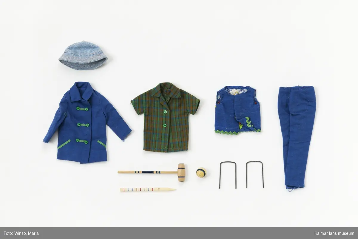 KLM45643:5 Dockdräkt, jacka, byxor, skjorta, väst, hatt och krocketspel. Jacka, blått tyg med gröna knappar och gröna dekorationer vid knappar och fickor, tryckknappar. Byxor, blått tyg med tryckknapp i midjan. Skjorta, rutig i grönt, blått och brunt med gröna knappar, kort ärm. Väst, av blått tyg kantad med grönt veckband nertill och med broderi med hjärta, fåglar och blommor på ryggen samt tryckknappar fram. Solhatt, av ljusblått tyg. Krocketset med klubba, två bågar av metall, pinne av trä och klot av trä. Blåa ballerina skor av plast med texten ”JAPAN” på sulan. Jackan märkt med Mattels etikett. Setet finns i häftet ”Barbie och hennes vänner – med många nya kläder” från Brio och heter ”920 Fun time”. Setet är för Skipper.
