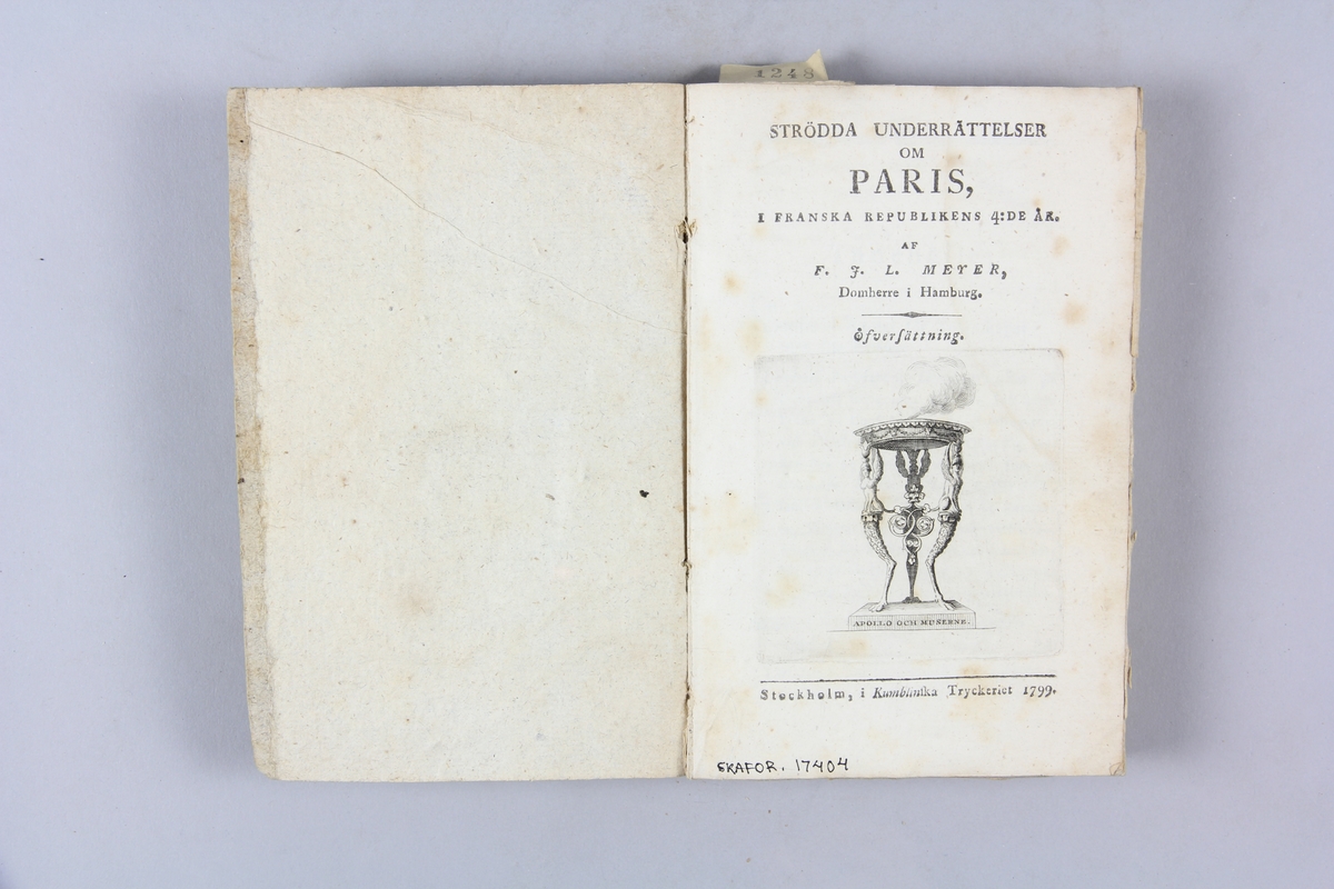 Bok, pappband, "Strödda underrättelser om Paris", tryckt 1799 i Stockholm. Pärmar av marmorerat papper, rygg med påskrift med bläck. Skuret snitt.