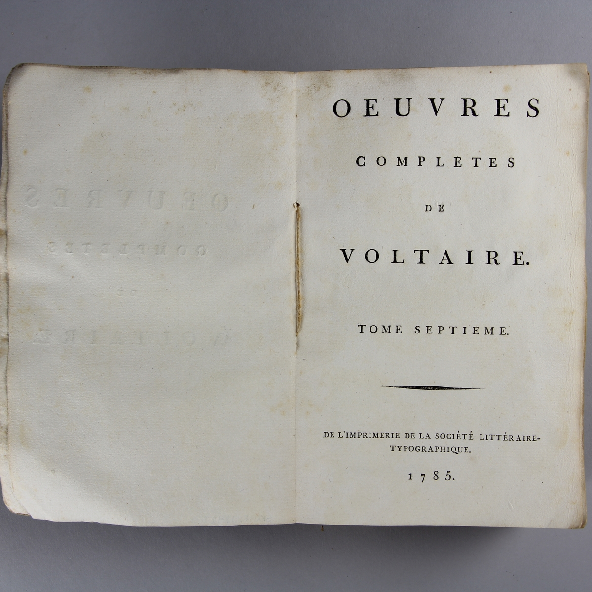 Bok, häftad,"Oeuvres complètes de Voltaire." del 7, tryckt 1785.
Pärm av gråblått papper, skurna snitt. På ryggen pappersetikett med tryckt text med volymens namn och nummer. Ryggen blekt.