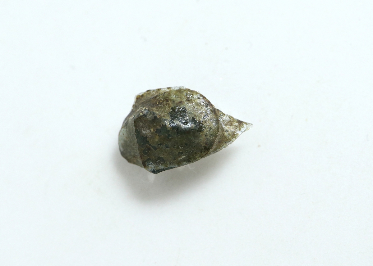 Fragment av en bägare eller pokal i form av en "glasnoppa". Mörkgrön glasmassa. Möjligen från ett nuppenglas eller en remmare av något slag.