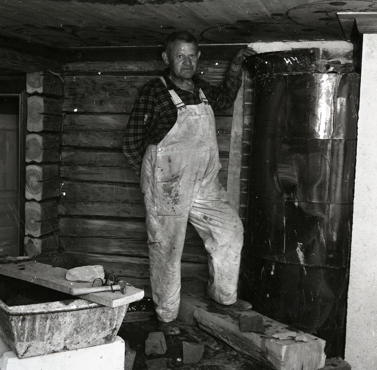 En man står vid en färdigbyggd kakelugn, 1968.