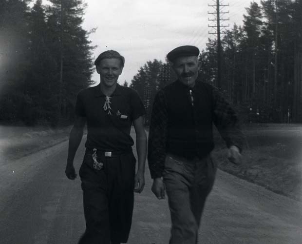 Två män varav en är Hilding Mickelsson vandrar längs en väg, 1940.