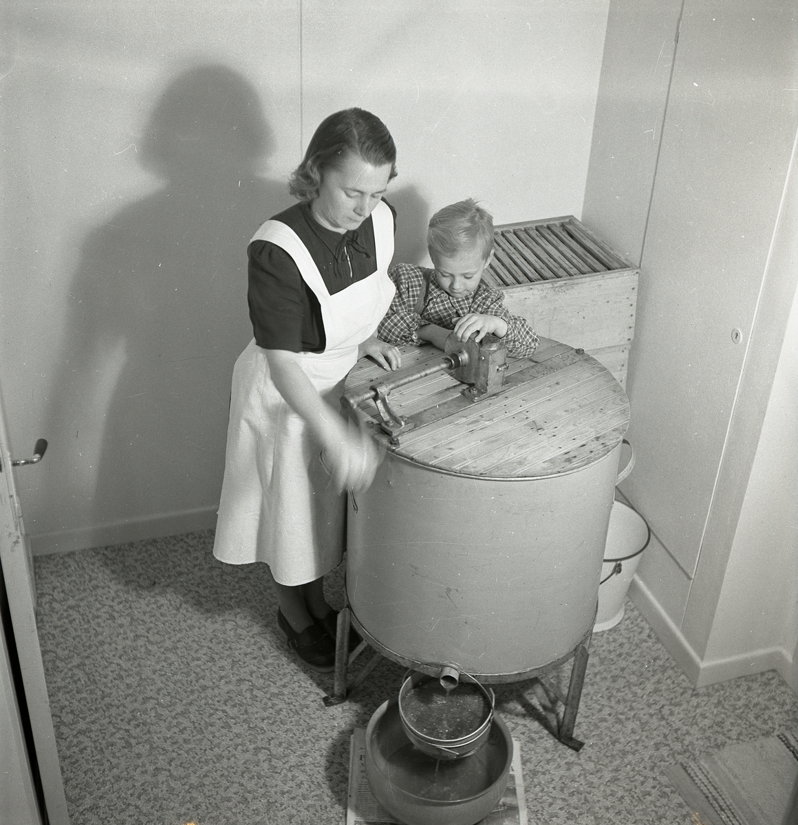 En kvinna och en pojke slungar honungsramar, november 1951.