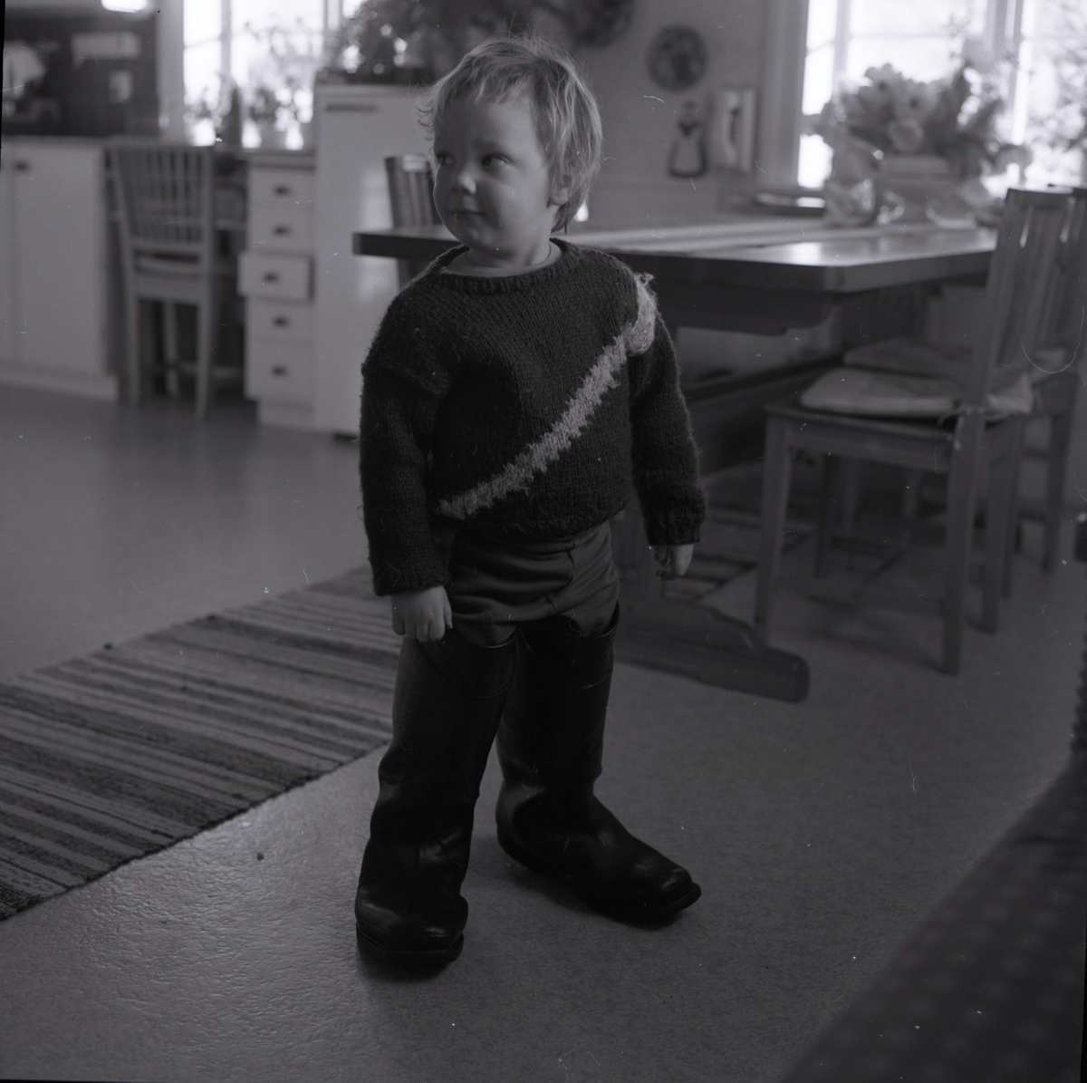 En pojke står i ett kök den 24 februari 1987.