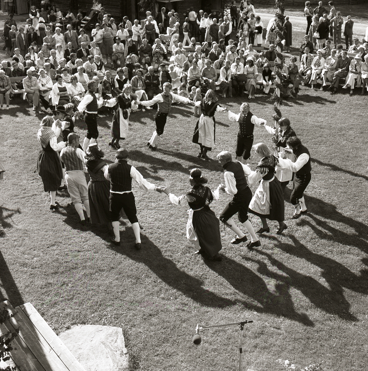 På en gräsmatta dansar en grupp människor iklädda hembygdsdräkter ringdans medan en publik ser på under Rengsjöfesten, 16 juli 1978.