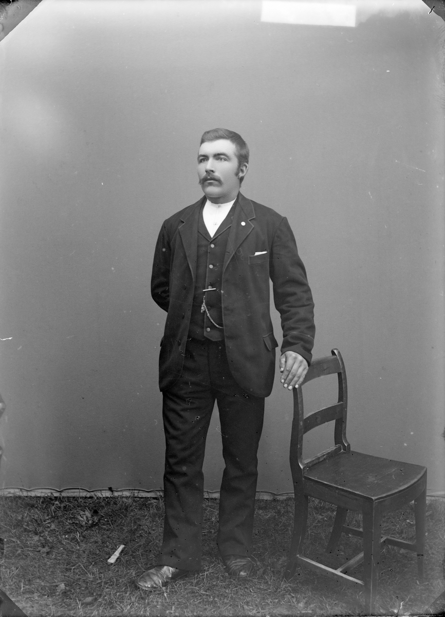 Mann med mørk dress og stol, atelierfoto.