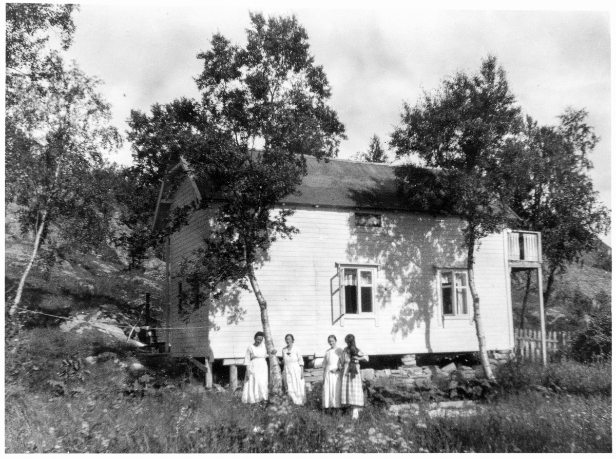 Fire kvinner utenfor et hus eller en hytte i Kanebogen.