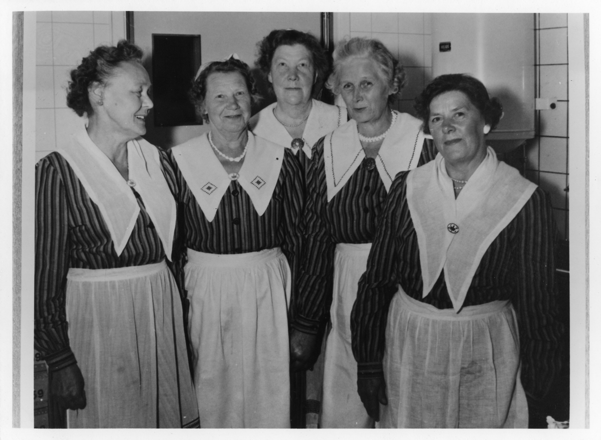 Gruppbild av Tillan Johansson (t.v.) tillsammans med fyra andra kvinnor från Kooperativa Kvinnogillet som inviger en Konsumbutik, troligtvis på Norra Strömgatan.
Originalbilden är mycket grå.