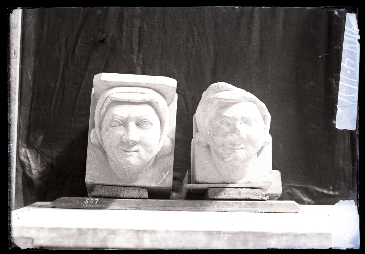 Maske, konsollsten fra korets gesims i Nidarosdomen. Ny og gammel konsoll ved siden av hverandre.

Originalskulpturen er utstilt i Museet Erkebispegården. 