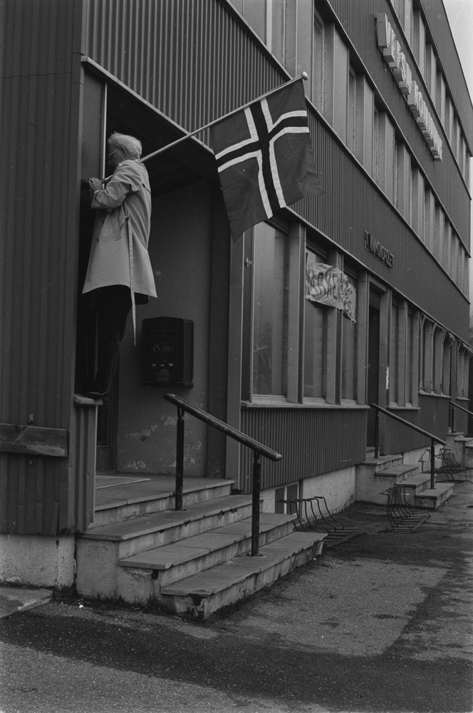 17 Mai. Mann som setter opp flagg på kommunehuset i Skjervgata. Der lå også Vinmonopolet i 1.etg.