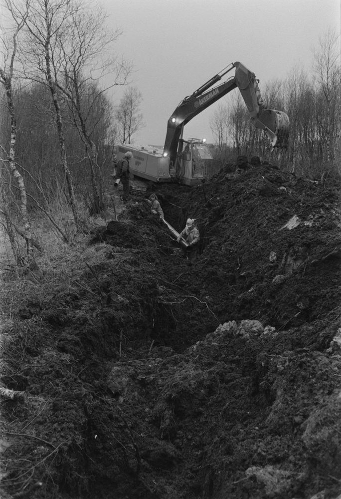 Legging av vannledning til Søvik. Gravemaskin som graver grøft og personer.