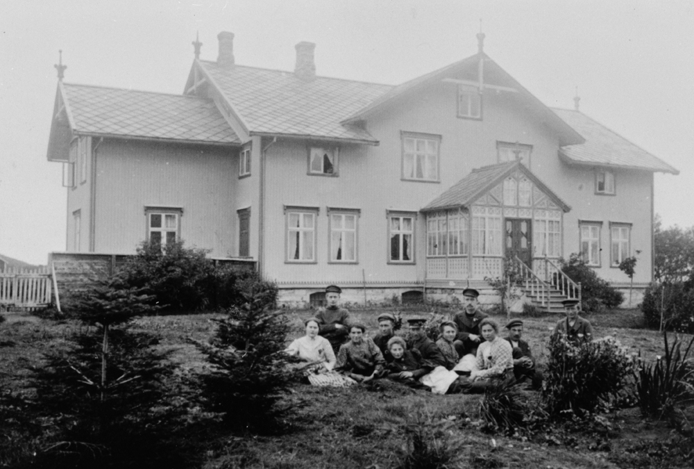 Hovedbygningen på Dønnes gård oppsatt i 1890, bildet er tatt i 1907. Gruppe sittende på plenen foran.