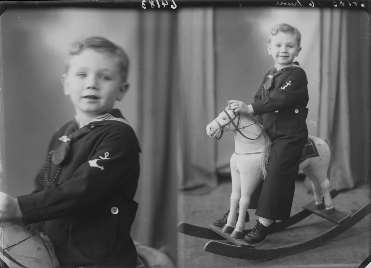 Portrett .Ung gutt med matrosdress og mørkt halstørkle poserer med hvit gyngehest og brodert stol. Bestilt av Olaf Økland. Sørhaugt. 111
