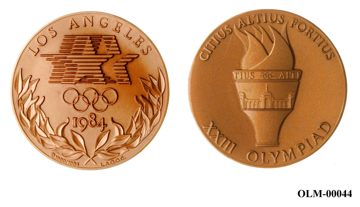 Rund medalje i bronse med fakkel og olympisk motto på den ene siden og logo for sommerlekene i Los Angeles 1984 med en seierskvist under på den andre siden. Medaljen ligger i en eske.