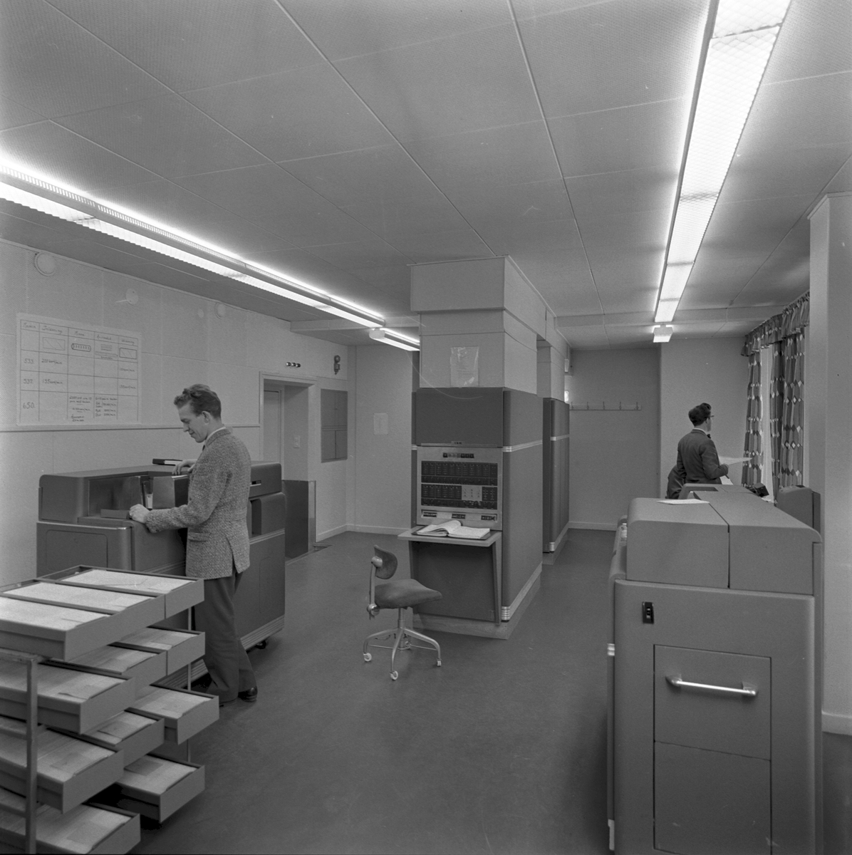 Datorrum vid Statens Järnvägar, SJ innehållandes en tidig IBM-dator med tillbehör. IBM 650 Magnetic Drum Data Processing Machine. I mitten syns användarkonsollen och till höger och vänster syns kombinerade hålkortläsare/skrivare, IBM 533 och/eller IBM 537.